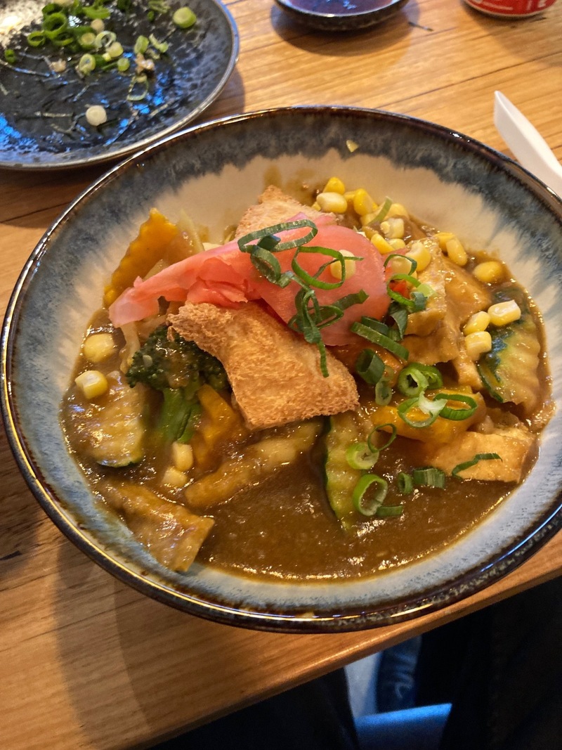 A dish of curry udon, with tofu, sweet corn, cucumber, and pickled ginger