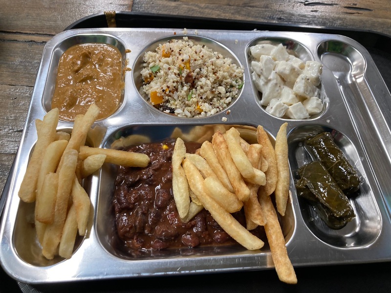 A buffet tray with curries, rice, chips, potato salad, and dolmades